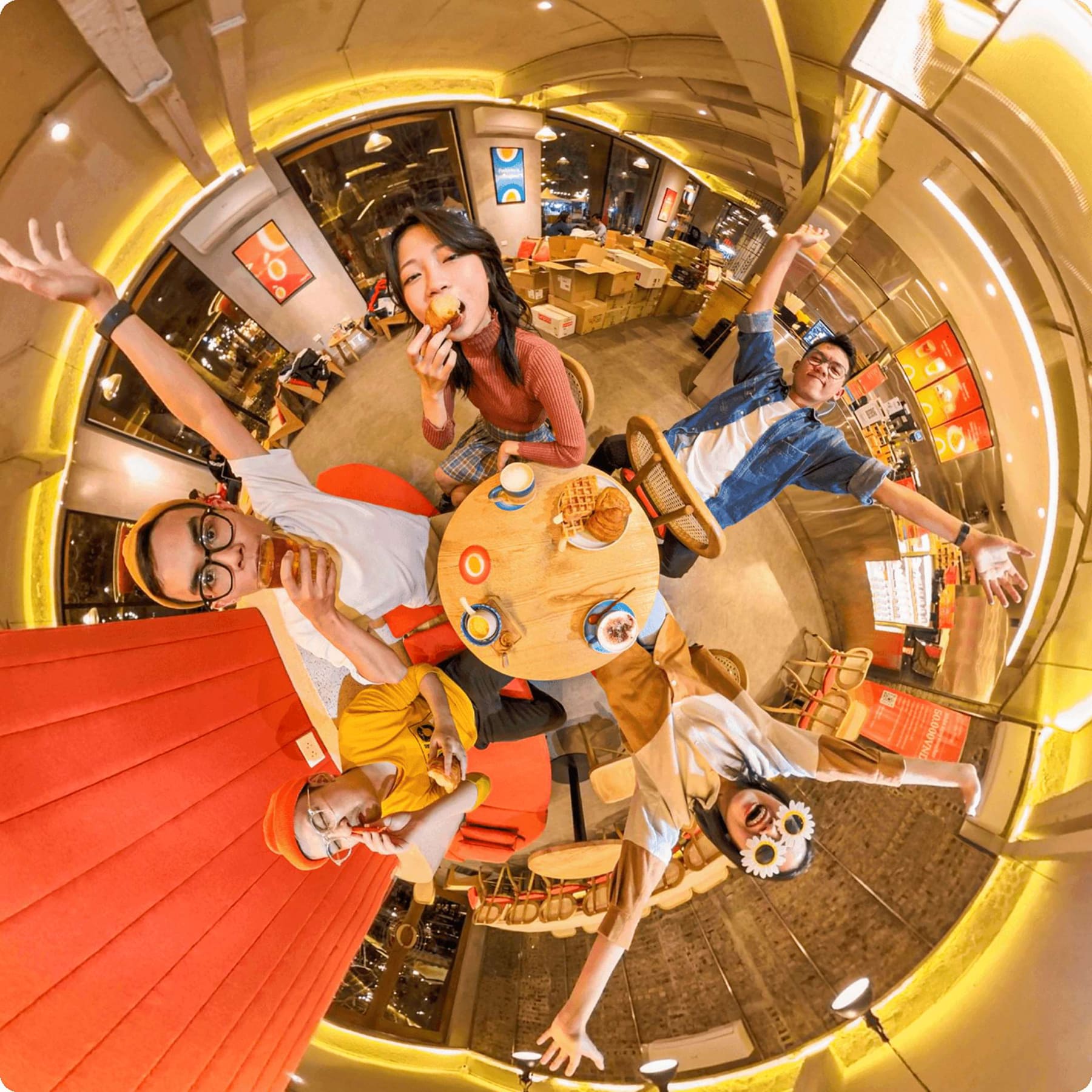 A fisheye view of friends laughing around a table inside an Eggyolk café