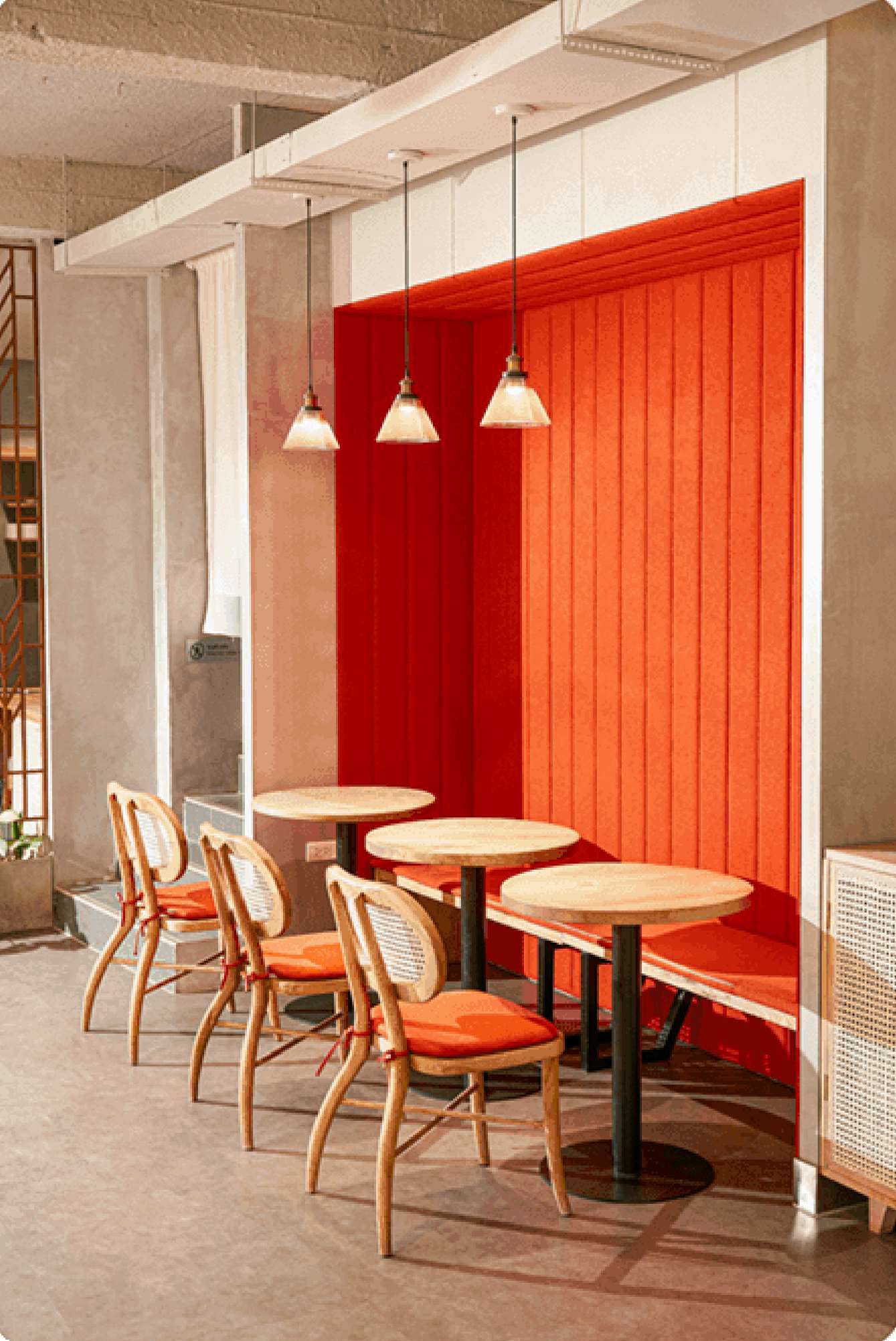 A bright orange booth with rattan chairs and pendant lamps